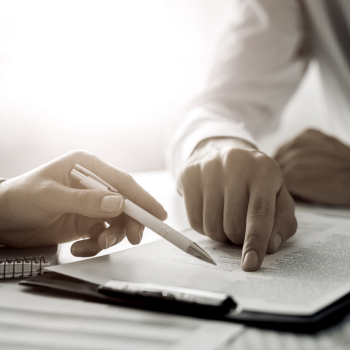 two people pointing on a piece of paper